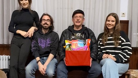 Die Mitglieder der Basisgruppe sitzen mit Geschenk im Jugendtreff